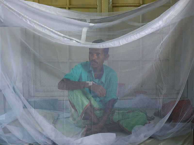 A dengue infected patient sits inside the mosquito net after being hospitalised at the Sir Salimullah Medical College Hospital in Dhaka, Bangladesh