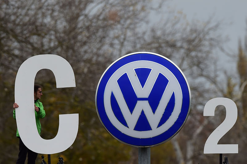 In this file photo taken on 9 November 2015, an activist of environmental organisation Greenpeace holds a giant letter to display `CO2` around the logo of German car maker Volkswagen (VW) at the entrance of the company`s headquarters in Wolfsburg, northern Germany.