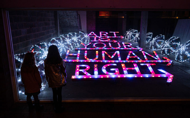 Members of the public view a piece of light-art entitled `Art Is Your Human Right` by artist Patrick Brill, also known as Bob and Roberta Smith, which features as part of the Lightpool Festival of visual arts in the centre of Blackpool, northern England on 14 October 2019.