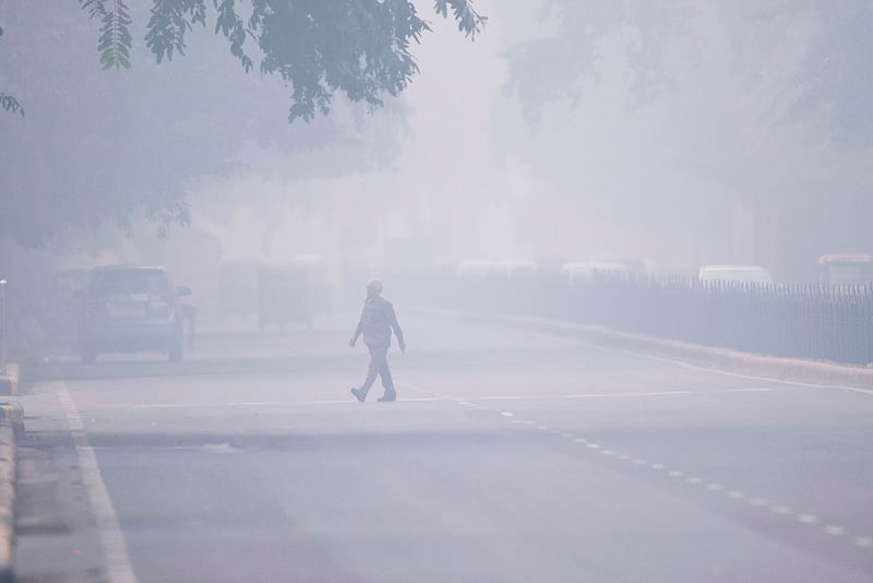 A man crosses a street in smoggy conditions in New Delhi on 4 November 2019. Millions of people in India`s capital started the week on 4 November choking through `eye-burning` smog, with schools closed, cars taken off the road and construction halted.