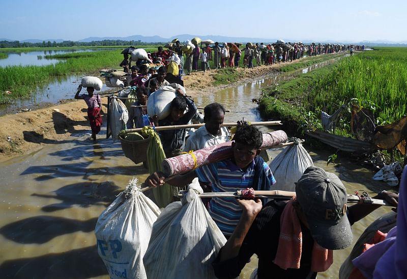 In this file photo taken on 3 November 2017, Rohingya Muslim refugees who were stranded after leaving Myanmar walk towards the Balukhali refugee camp after crossing the border in Bangladesh's Ukhiya district