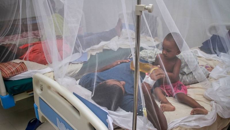 Dengue patients are seen inside mosquito curtains at a hospital