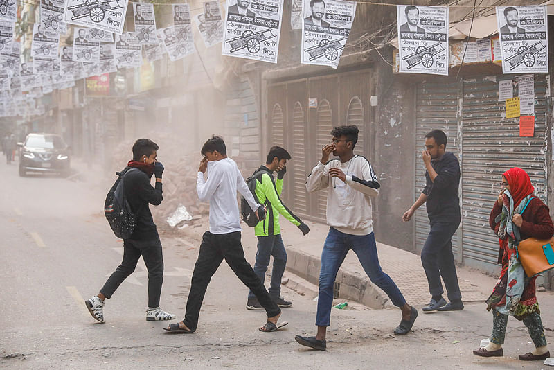 Passersby choking on dust from a building which being demolished. This photo taken from Mohammadpur area, Dhaka, on 18 January 2020.