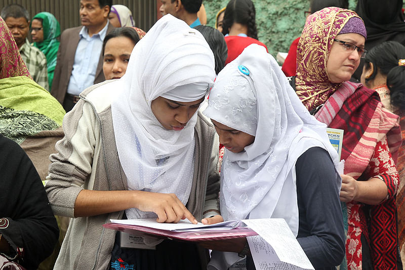 পরীক্ষা কেন্দ্রে বই নিয়ে যাওয়া নিষেধ। তাই হলে প্রবেশের আগে শেষ মুহূর্তে গুরুত্বপূর্ণ বিষয়গুলোতে চোখ বুলিয়ে নিচ্ছে দুই পরীক্ষার্থী। ছবিটি তেজগাঁও এলাকার সরকারি বিজ্ঞান কলেজের সামনে থেকে তোলা। ছবি: সাহাদাত পারভেজ