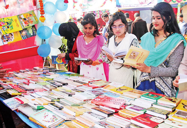 বগুড়ার সরকারি আজিজুল হক কলেজ চত্বরে কলেজ প্রশাসনের আয়োজনে অমর একুশে গ্রন্থমেলা গতকাল বিকেলে উদ্বোধন করা হয়। মেলার একটি স্টলে বই দেখছেন কয়েকজন l ছবি: প্রথম আলো