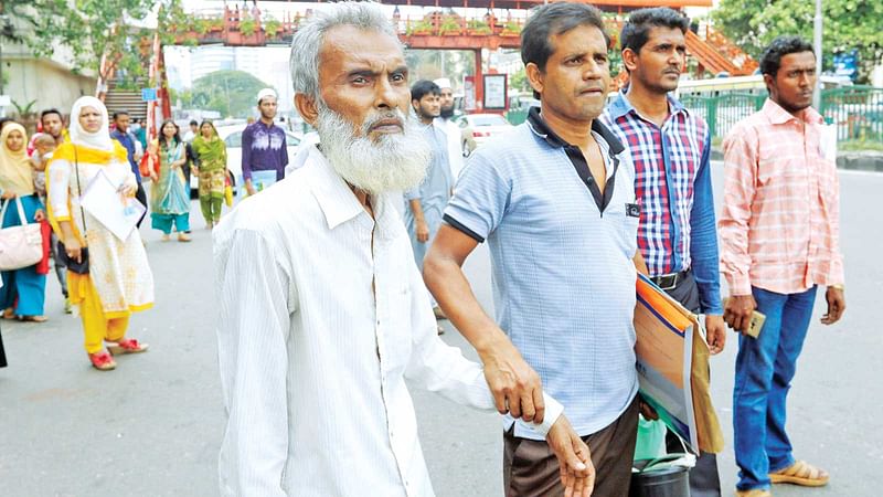 ক্যানসারের রোগী সুলতান মিয়াকে (বাঁয়ে) নিয়ে মহাখালীর ক্যানসার হাসপাতালে যেতে প্রায় এক ঘণ্টা শাহবাগ মোড়ে বাসের অপেক্ষায়  দাঁড়িয়ে ছিলেন হারুন উর রশিদ। এ সময় বাসের অপেক্ষায় আরও অনেকেই সেখানে দাঁড়িয়ে ছিলেন। ছবিটি গতকাল দুপুরে তোলা l আবদুস সালাম