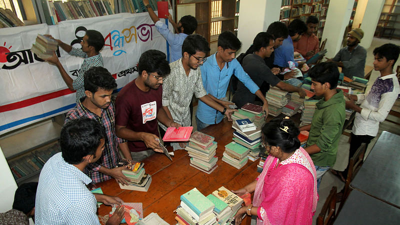 বগুড়া শহরের পৌর পার্ক-সংলগ্ন উডবার্ণ সরকারি গণগ্রন্থাগারের সেলফে থাকা বই নামিয়ে ধূলিবালি পরিষ্কার করছেন বগুড়া বন্ধুসভার সদস্যরা। ছবি: সোয়েল রানা