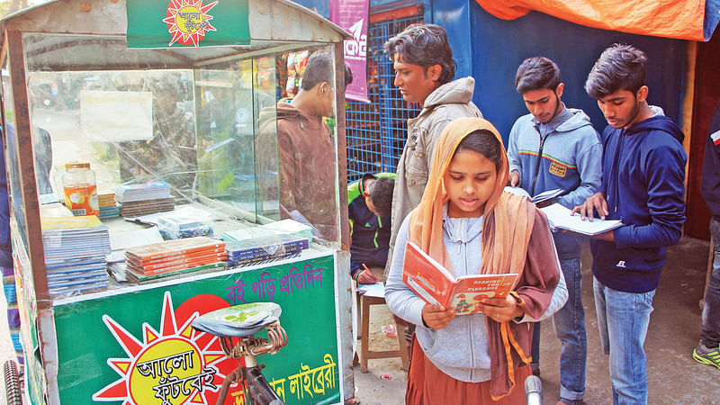 এস এম আলমগীর হোসেনের ভ্রাম্যমাণ লাইব্রেরি থেকে বই সংগ্রহ করছে আগ্রহী পাঠকেরা।  ছবি: সাদ্দাম হোসেন