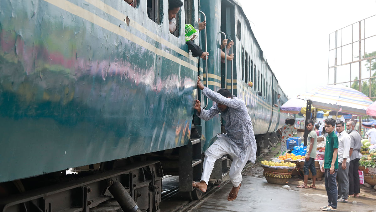 ট্রেন চলা শুরু করেছে। এ অবস্থায় ঝুঁকি নিয়ে এক ব্যক্তি ট্রেনে উঠছেন। আশকোনা, ঢাকা, সাম্প্রতিক ছবি। ছবি: প্রথম আলো