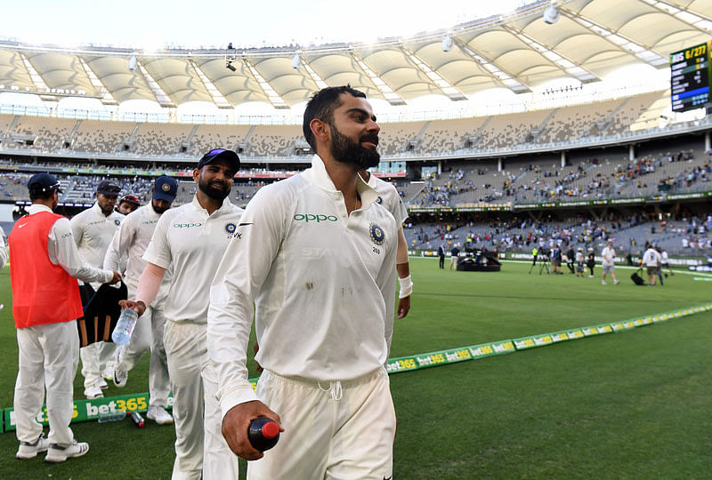 প্রথম দিনের খেলা শেষে হাসিমুখেই মাঠ ছাড়ছেন কোহলি। ছবি: এএফপি