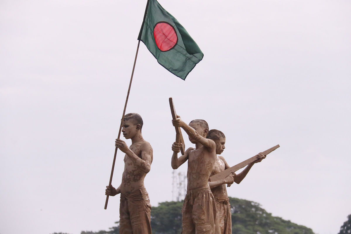 দেখে মনে হয় ভাস্কর্য। কিন্তু আসলে দাঁড়িয়ে আছে তিন শিশু। হাতে উড়ছে বিজয়ের পতাকা। সিলেট জেলা স্টেডিয়াম, সিলেট, ১৬ ডিসেম্বর। ছবি: আনিস মাহমুদ