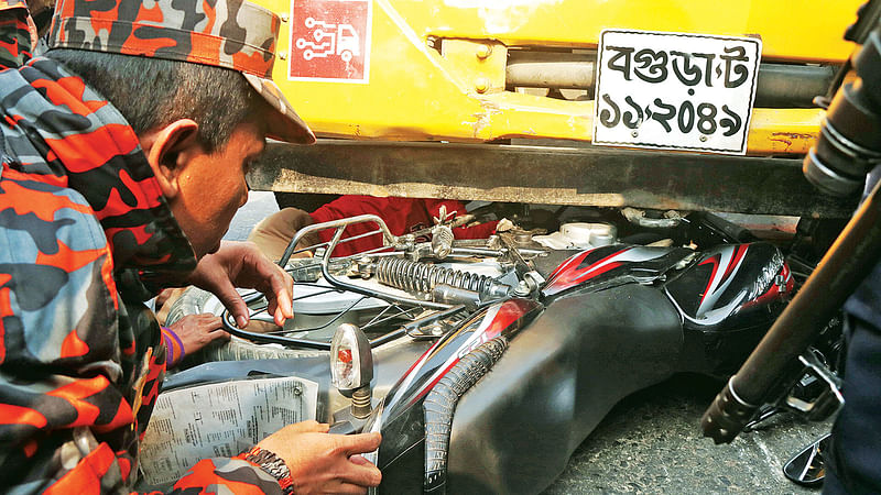 মোটরসাইকেল ও পণ্যবাহী ট্রাকের সংঘর্ষে মোটরসাইকেলচালকসহ তিন আরোহী আহত হন। ট্রাকের নিচ থেকে মোটরসাইকেল উদ্ধারের চেষ্টা করছেন পুলিশের সদস্যরা। গতকাল সকালে বগুড়া-ঢাকা মহাসড়কের বেতগাড়ী এলাকায়।  ছবি: সোয়েল রানা