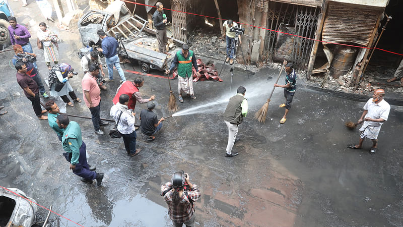 চকবাজারে আগুনে পোড়া ক্ষতিগ্রস্ত ভবন ও সামনের সড়ক ধুয়েমুছে পরিষ্কার করা হচ্ছে। ছবি: আবদুস সালাম