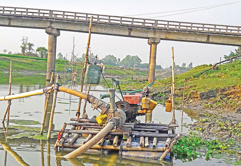 বাগমারার খাজাপাড়া-বাগমারা সংযোগ সেতুর নিচ থেকে মাসাধিককাল ধরে এভাবে ড্রেজার মেশিন দিয়ে বালু তুলছে এলজিইডি। গত সোমবার বিকেলে।  ছবি: প্রথম আলো