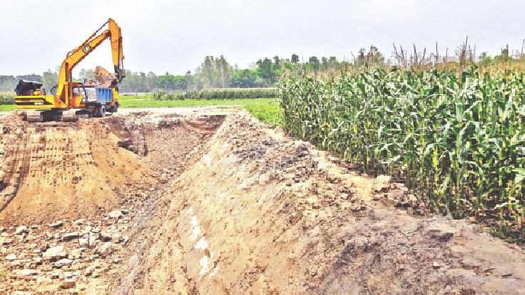 মানিকগঞ্জের ঘিওরের পুরানগ্রামে একটি ব্যবসায়িক প্রতিষ্ঠান তাদের কেনা জমিতে খননযন্ত্র দিয়ে গভীর গর্ত খুঁড়ছে। এতে পাশের ফসলি জমি ভাঙনের ঝুঁকিতে পড়েছে।  ছবি: প্রথম আলো