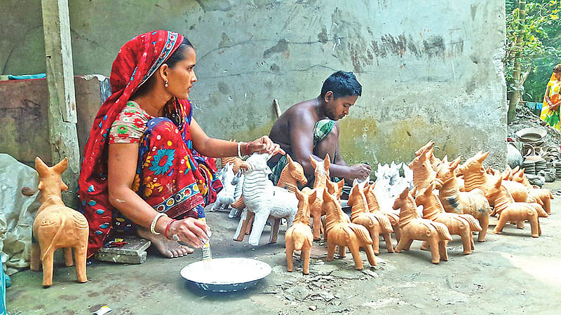 পয়লা বৈশাখ সামনে রেখে মাদারীপুর সদর উপজেলার পালপাড়ায় মাটির খেলনাসামগ্রী তৈরি করছেন মৃৎশিল্পীরা।  ছবি: প্রথম আলো