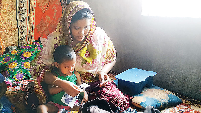 নিহত সন্তান মনিরের স্মৃতি হাতড়ে বেড়াচ্ছেন মা। কোলে আরেক সন্তান মাইশা।  ছবি: প্রথম আলো