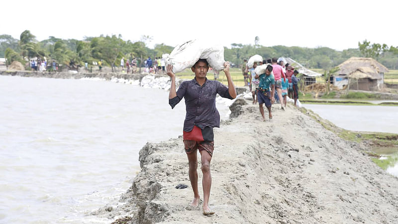 বালুর বস্তা ফেলে বাঁধ মেরামতের কাজ চলছে। ছবি: শুভ্র কান্তি দাশ