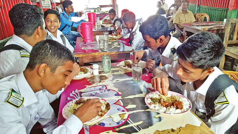 রাজশাহীর বাঘা উপজেলার আড়ানী বাজারে অন্নপূর্ণা হোটেল অ্যান্ড রেস্টুরেন্টে পাঁচ টাকার প্যাকেজের খাবার খাচ্ছে স্কুলশিক্ষার্থীরা। ছবিটি গত বৃহস্পতিবার তোলা।  প্রথম আলো