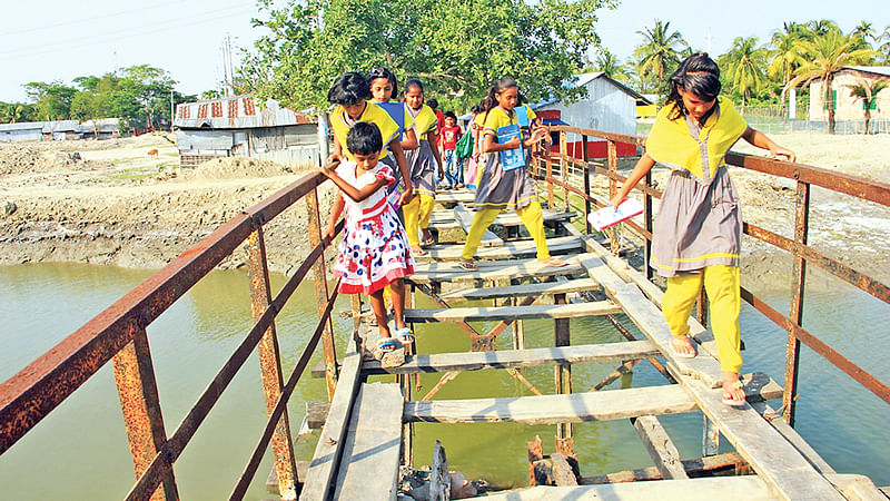 বাগেরহাটের মোংলা বন্দর পৌরসভার মাছমারা খালের ওপরের কাঠের সেতুটি অত্যন্ত জরাজীর্ণ। শিশুরা এটি পার হয় ভয়ে ভয়ে। গত সোমবার মাছমারা গ্রামে।  ছবি: প্রথম আলো