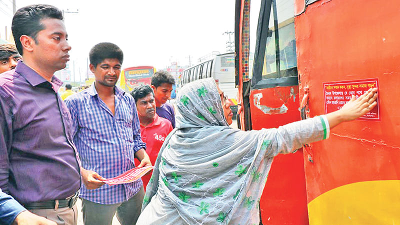 গণপরিবহনে যৌন হয়রানি রোধে সচেতনতামূলক স্টিকার সাঁটাচ্ছেন ভৈরবের ইউএনও। গতকাল ভৈরব বাসস্ট্যান্ড এলাকায়।  ছবি: প্রথম আলো