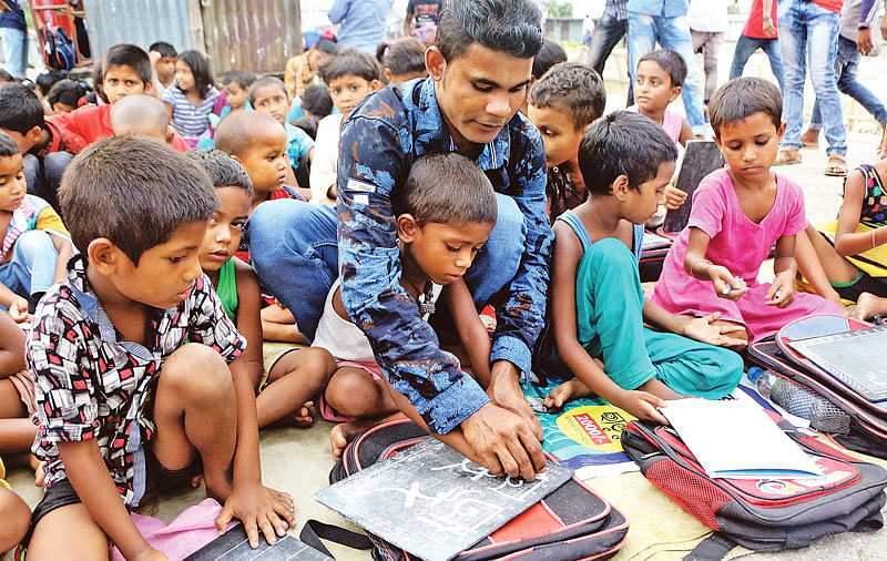 শিশুদের লেখা শেখাচ্ছেন শুভ চন্দ্র দাস। গত মঙ্গলবার বিকেলে নারায়ণগঞ্জের চাষাঢ়া  রেলস্টেশন এলাকায়।  ছবি: দিনার মাহমুদ