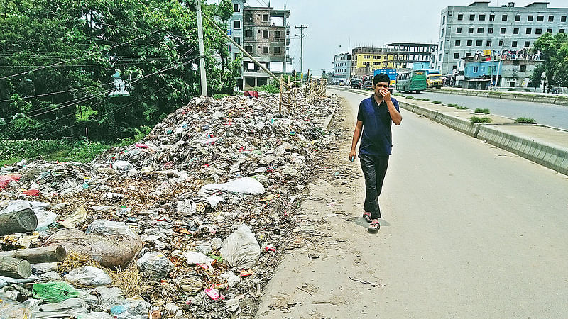 রাস্তার পাশে ময়লার স্তূপ। তাতে দুর্গন্ধে একাকার এলাকা। হাত দিয়ে নাক চেপে ধরে এলাকা পার হচ্ছেন এক পথচারী। গতকাল দুপুরে ঢাকা-টাঙ্গাইল মহাসড়কের মির্জাপুর উপজেলার গোড়াই শিল্পাঞ্চলের রণারচালা এলাকায়।  ছবি: প্রথম আলো