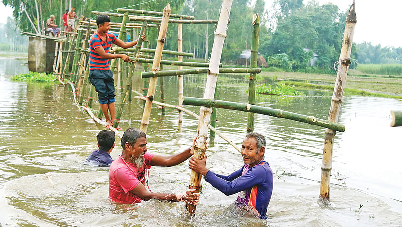 গঙ্গাচড়ার ইছলি এলাকায় সংযোগ সড়ক ভেঙে গেছে। সেখানে এলাকাবাসী বাঁশ দিয়ে সাঁকো তৈরি করছেন। গতকাল পূর্ব ইচলি এলাকায়।  প্রথম আলো