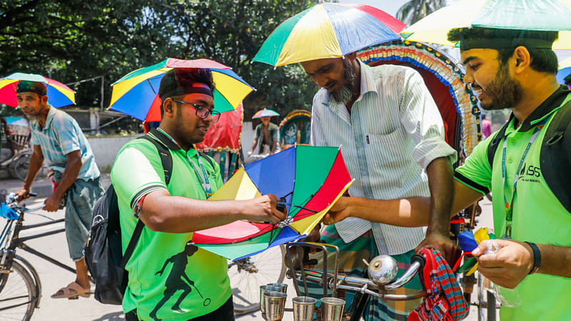 ঢাকার ফার্মগেট এলাকায় ছাতা বিতরণ করছেন লাল-সবুজ সোসাইটির সদস্যরা। ছবি: দীপু মালাকার