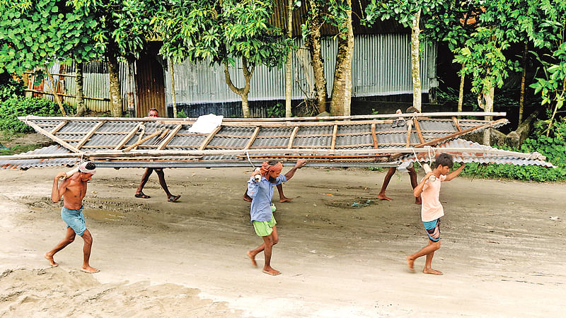 যমুনায় পানি বাড়ছে। তাই গতকাল বগুড়ার সারিয়াকান্দি উপজেলার রৌহদহ গ্রামের ঘরের চালা অন্যত্র সরিয়ে নিচ্ছেন লোকজন।  ছবি: সোয়েল রানা