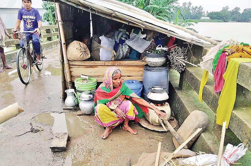 বন্যায় ঘর ভাসিয়ে নিয়েছে। শেষ সম্বলটুকু নিয়ে সেতুর ওপর আশ্রয় নিয়েছেন মনিরা বেগম। গতকাল দুপুরে ইসলামপুর উপজেলার আমতলী সেতুর ওপর।  ছবি: প্রথম আলো