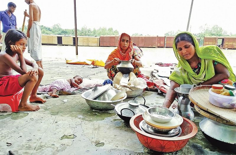 কাছে আছে সামান্য কিছু চাল। সেই চাল চুলায় বসিয়ে ক্ষুধার্ত সন্তানদের সান্ত্বনা দেওয়ার চেষ্টা করছেন মা। গতকাল দুপুরে দেওয়ানগঞ্জ রেলস্টেশনের প্ল্যাটফর্মের ওপর।  ছবি: প্রথম আলো