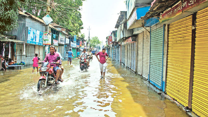 বন্যায় ১৯৮৮ সালের পর এই প্রথম গাইবান্ধা শহরের বিস্তীর্ণ এলাকায় পানি প্রবেশ করেছে। গতকাল বিকেলে গাইবান্ধা জেলা শহরের ব্যস্ততম স্টেশন রোডের থানপট্টি এলাকায়।  ছবি: প্রথম আলো