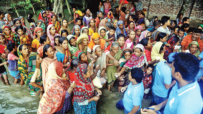 গাইবান্ধায় বেসরকারিভাবে কিছু জায়গায় ত্রাণ দেওয়া হচ্ছে। গতকাল সদর উপজেলার কালীর বাজার এলাকায়।  ছবি: প্রথম আলো