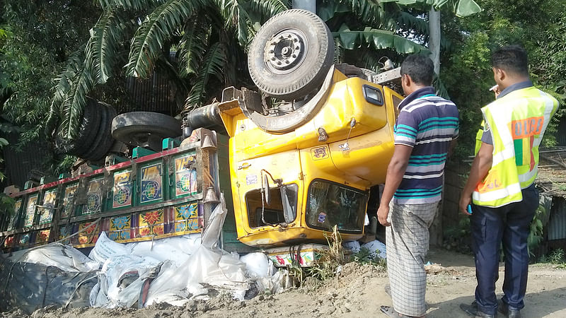 টাঙ্গাইলের মির্জাপুর উপজেলার হাতকুড়া এলাকায় উল্টে যাওয়া সারবোঝাই ট্রাক। ছবিটি আজ বুধবার সকাল আটটার দিকে তোলা। ছবি: প্রথম আলো