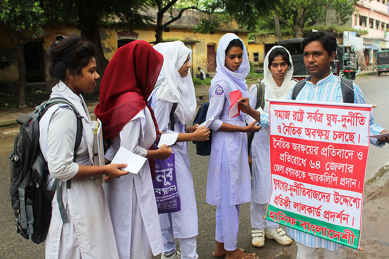 ঘুষ-দুর্নীতি ও নৈতিক অবক্ষয়ের বিষয়ে শিক্ষার্থীদের সচেতন করছেন মো. হানিফ। সেই সঙ্গে ঘুষখোর ও দুর্নীতিবাজদের উদ্দেশ্যে লাল কার্ড প্রদর্শন করেন তিনি। চুয়াডাঙ্গা, ২৪ সেপ্টেম্বর। ছবি: শাহ আলম