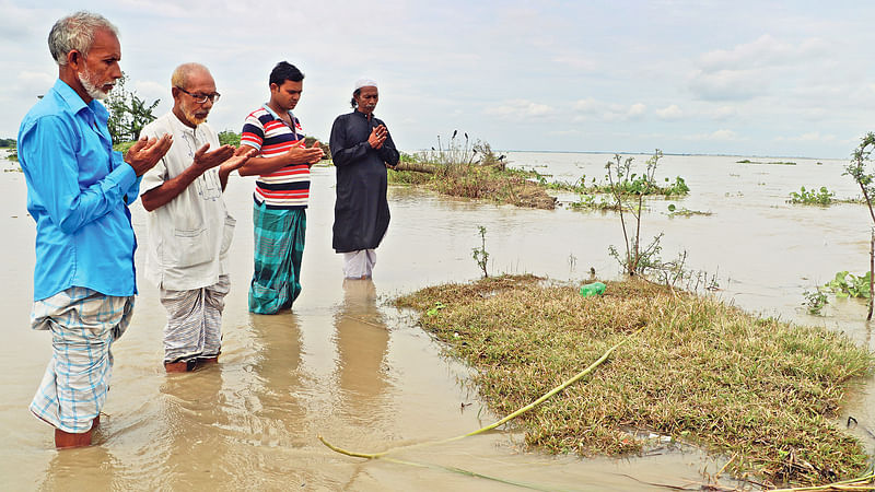 ভাঙনে অবশিষ্ট বসতভিটার পাশে থাকা মায়ের কবরটাও যেকোনো মুহূর্তে নদীতে বিলীন হয়ে যাবে। তাই জুমার নামাজের পর শেষবারের মতো তিন ভাই ও স্বজনের কবর জিয়ারত। গত শুক্রবার দুপুরে রাজবাড়ীর গোয়ালন্দের দেবগ্রামে।  ছবি: এম রাশেদুল হক