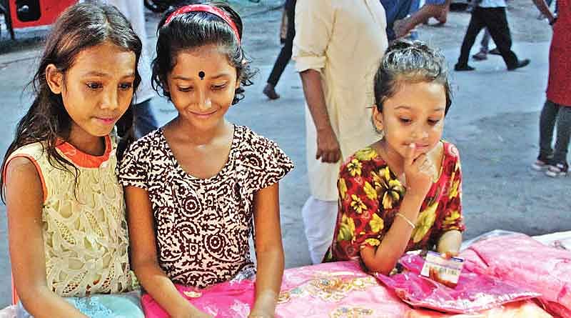 সাত টাকার জামা দেখছে শিশুরা। গতকাল রমনা কালীমন্দির এলাকায়।  প্রথম আলো