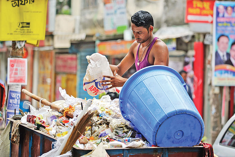 সংগ্রহ করা আবর্জনা রাখা হচ্ছে ভ্যানে। সম্প্রতি লালমাটিয়ায়।  ছবি: জাহিদুল করিম