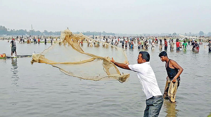 শুক নদের বুড়ির বাঁধ (জলকপাট) খুলে দেওয়ার পর মাছ ধরতে নেমে পড়েন মানুষ। গতকাল সকালে ঠাকুরগাঁও সদর উপজেলায়।  প্রথম আলো