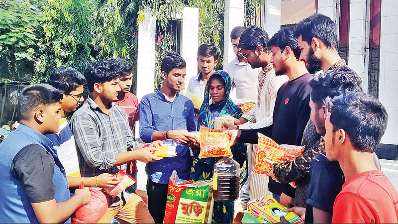 অসহায় মায়ের হাতে বিভিন্ন সামগ্রী তুলে দিচ্ছেন তরুণেরা।  ছবি: প্রথম আলো