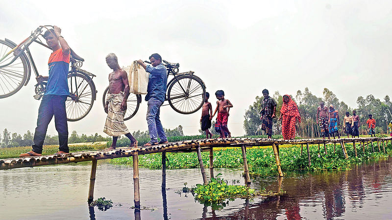 যমুনেশ্বরী নদীতে সেতু নির্মাণ না হওয়ায় লোকজন বাঁশের তৈরি পুরোনো নড়বড়ে সাঁকো দিয়ে ঝুঁকি নিয়ে পারাপার হচ্ছে। রংপুরের তারাগঞ্জ উপজেলার জয় বাংলা ঘাটে।  ছবি: প্রথম আলো