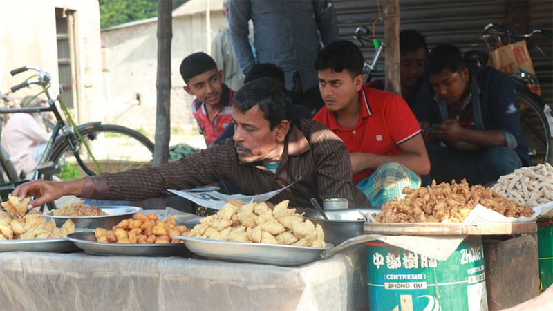 শিঙাড়াসহ তেলে ভাজা নানা ধরনের খাবার নিয়ে বসে আছেন দোকানি। সম্প্রতি মাগুরা সদরের গাংনালিয়া বাজারে।  ছবি: প্রথম আলো