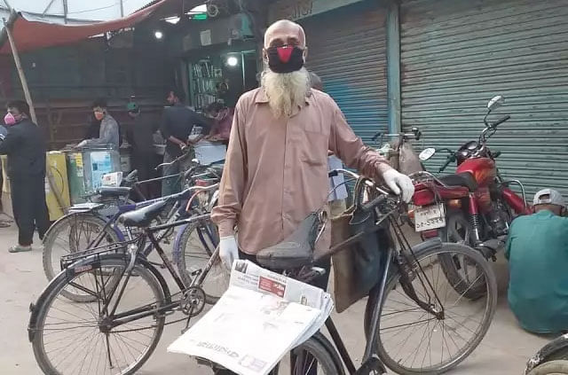 মানুষের দোড়গোড়ায় নিরাপদে পত্রিকা পৌঁছে দেওয়ার কাজ করছেন হকার। ছবি: প্রথম আলো