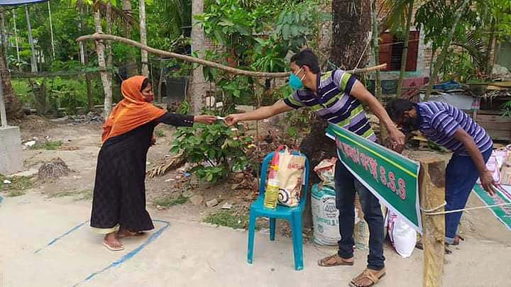 ঝালকাঠির কৃষ্ণকাঠি বাসটার্মিনাল এলাকার স্বপ্নপূরণ সমাজকল্যাণ সংস্থার সদস্যরা এক নারীর হাতে খাদ্যসামগ্রী তুলে দিচ্ছেন। গতকাল শুক্রবার তোলা। ছবি: প্রথম আলো