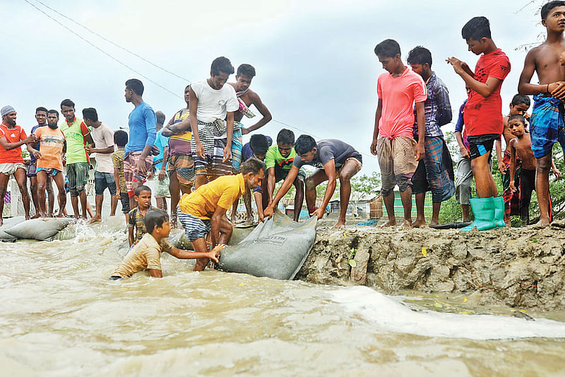 বালুর বস্তা দিয়ে ক্ষতিগ্রস্ত বাঁধ মেরামতের চেষ্টা করছেন এলাকাবাসী। গতকাল সকালে সাতক্ষীরার শ্যামনগর উপজেলার গাবুরায়।  সাইফুল ইসলাম