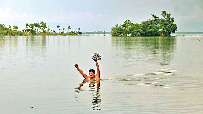 পানিবন্দী গ্রাম থেকে বুকপানি ঠেলে যাতায়াত করছে মানুষ। গত শনিবার সিলেটের গোয়াইনঘাটের সালুটিকর এলাকায়।  ছবি: প্রথম আলো