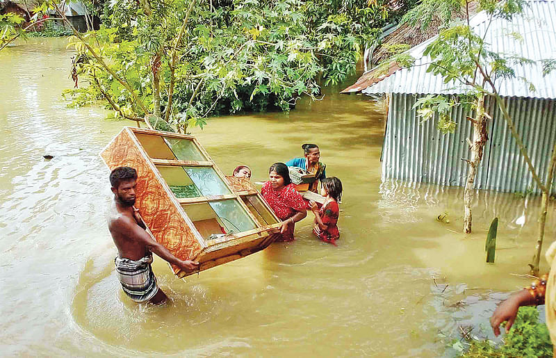 বাঁধভাঙা পানিতে ডুবে গেছে ঘরবাড়ি। আসবাব নিয়ে নিরাপদ আশ্রয়ে ছুটছেন গ্রামবাসী। গতকাল দুপুরে নওগাঁর মান্দা উপজেলার কয়লাবাড়ী এলাকায় ।  ছবি: ওমর ফারুক