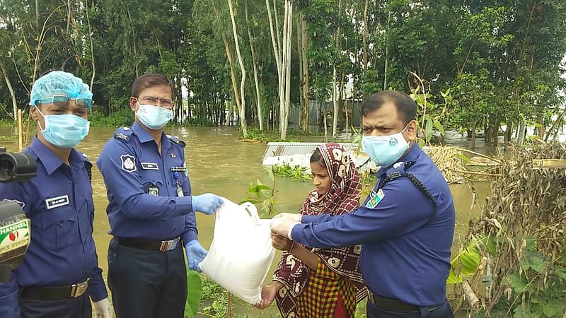 বাড়ি বাড়ি গিয়ে বন্যার্ত পরিবারগুলোর মধ্যে ১০ কেজি করে চালের ব্যাগ তুলে দেন নাটোর জেলা পুলিশ সদস্যরা। ছবি: প্রথম আলো