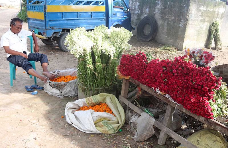 যশোরের গদখালী বাজারের এক ব্যবসায়ী দোকানে ফুল সাজিয়ে রেখেছেন। কিন্তু ক্রেতা না থাকায় অলস সময় পার করছেন তিনি। গত সোমবার তোলা। ছবি: এহসান-উদ-দৌলা